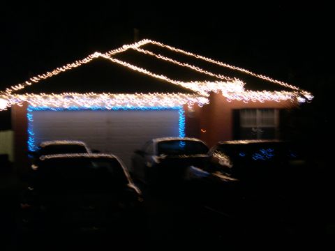 1997 Ford Probe - Several cars are parked in a driveway at night, illuminated by the glow of Christmas lights decorating the house.