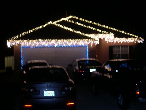 1997 Ford Probe - A house is adorned with festive Christmas lights, with several vehicles parked in front.