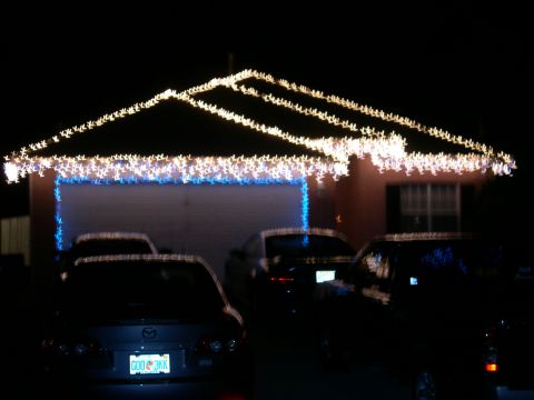 1997 Ford Probe - Multiple vehicles are parked in front of a house adorned with festive holiday lights.