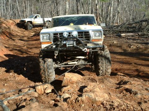 1992 Ford Mustang - A heavily modified 1979 Ford F-Series truck navigates a rocky, off-road trail, with another truck visible in the background.
