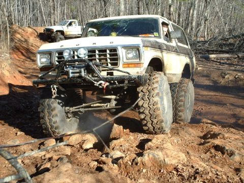 1992 Ford Mustang - Modified Ford Bronco navigating a challenging off-road trail with a second vehicle in the background.
