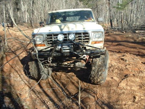 1992 Ford Mustang - This modified Ford Bronco is navigating a rough, wooded terrain with a winch mounted on the front.