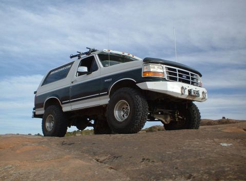 1993 Ford Bronco - This 1993 Ford Bronco is equipped with a custom front bumper and roof rack, parked on a rocky surface.