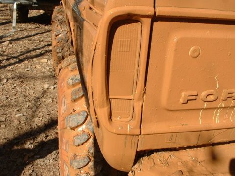 1992 Ford Mustang - This heavily muddied truck's rear section shows a taillight and part of the Ford emblem, with large off-road tires.