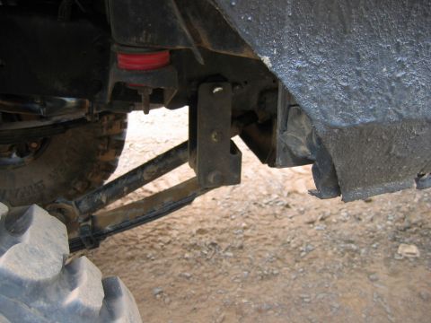 1992 Ford Mustang - Detail of vehicle suspension system, including a tire and red bushings, viewed from below.