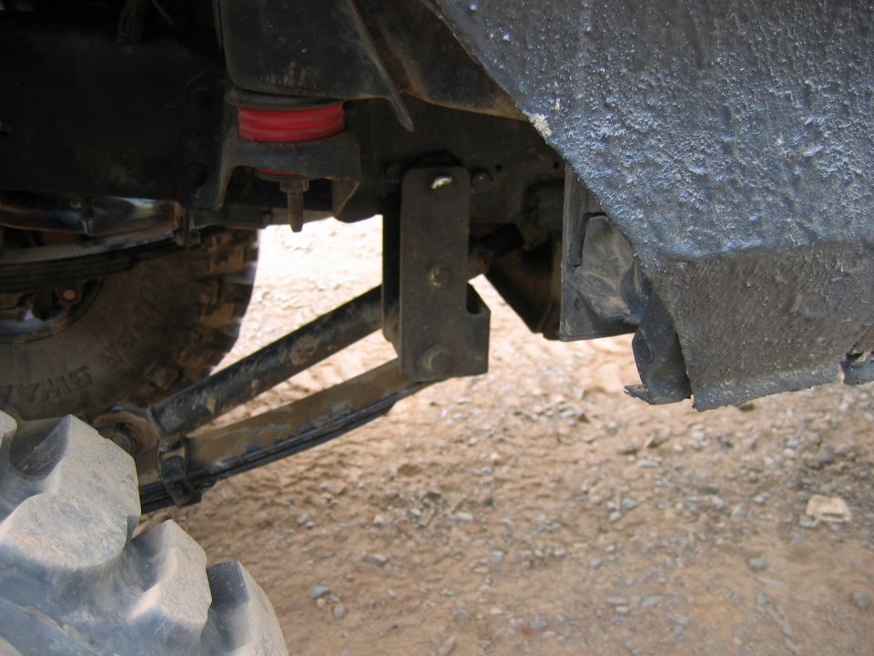 Close-up of suspension components and tire, showing red bushings