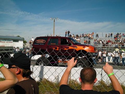 1986 Ford Bronco - Monster truck with flames and "FOR SALE" sign is displayed at a drag strip event.