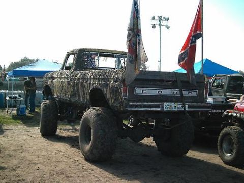 1986 Ford Bronco - A lifted Ford pickup truck with Confederate flags flies in the bed.