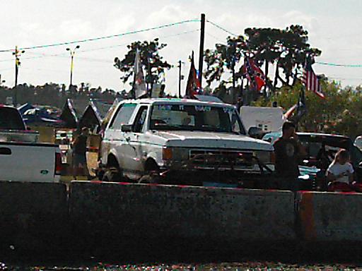 White 1986 Ford Bronco with flags on roof and antenna