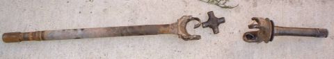 1993 Ford Bronco - Two halves of a front drive axle shaft laid on concrete, showing the longer inner shaft with its U-joint yoke and cross and the shorter out…