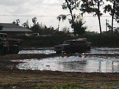 1986 Ford Bronco - A Ford Bronco navigates a muddy track, with another vehicle partially visible on the left.