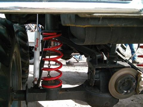 1986 Ford Bronco - Close-up view of a vehicle's modified suspension system, bright red coil springs and a prominent Rancho shock absorber.