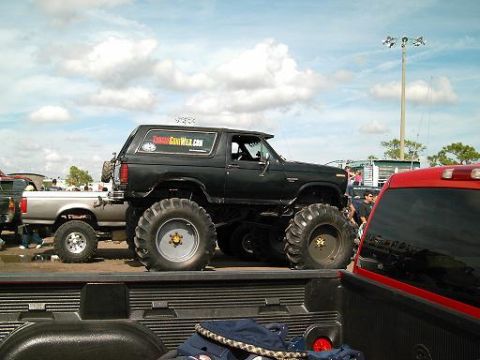 1986 Ford Bronco - A lifted black Bronco with large off-road tires is parked at an outdoor event.