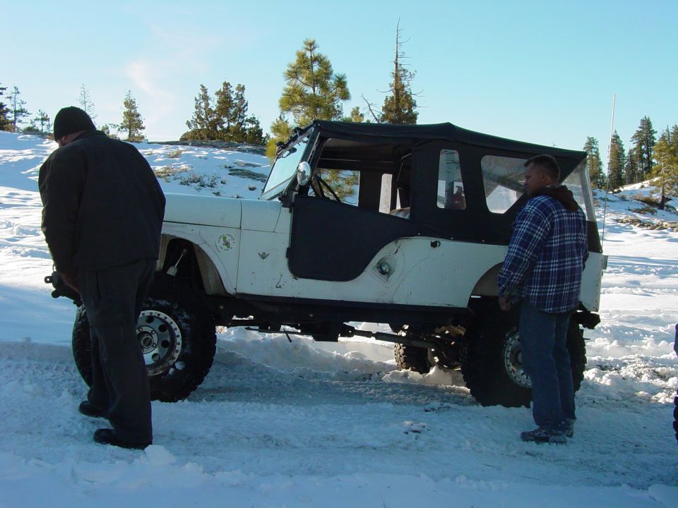White Jeep CJ-7 with soft top in snow, side view