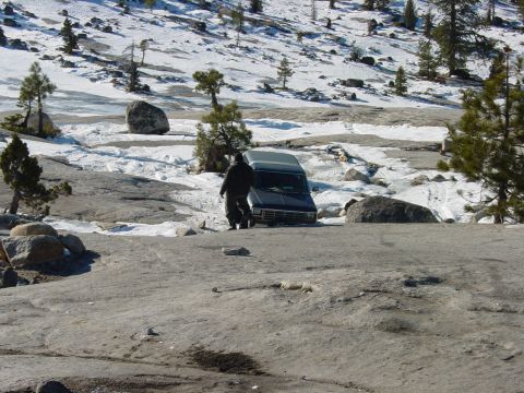 1986 Ford Bronco - A person approaches a van in a snowy, rocky terrain.