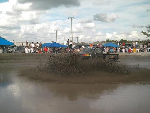 1986 Ford Bronco - Spectators watch as a truck navigates a muddy track.