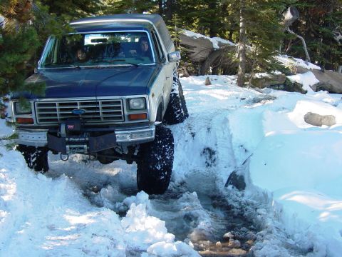 1986 Ford Bronco - This Ford Bronco navigates a snowy trail with its front end angled towards the camera.