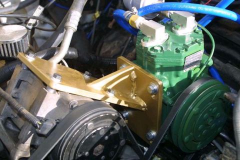 1993 Ford Bronco - Engine-bay close-up of a green-painted York-style compressor converted to an on-board air setup, bolted to a fabricated gold-painted steel…