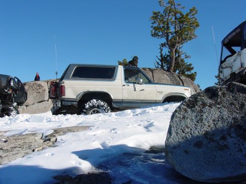 1986 Ford Bronco - A 1986 Ford Bronco is seen off-roading in a snowy environment, with another vehicle nearby.