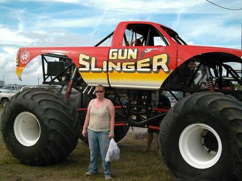 1986 Ford Bronco - A woman poses next to the 'Gun Slinger' monster truck at an outdoor event.