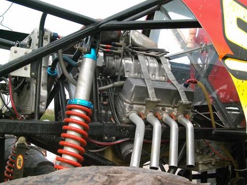 1986 Ford Bronco - This image shows the engine compartment of a modified vehicle, a supercharger and custom exhaust.