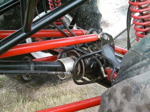 1986 Ford Bronco - Close-up view of the suspension system and large tire of a custom off-road vehicle.