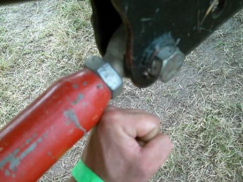 1986 Ford Bronco - Close-up of a red painted metal rod and a bolt assembly, possibly part of a vehicle's suspension.
