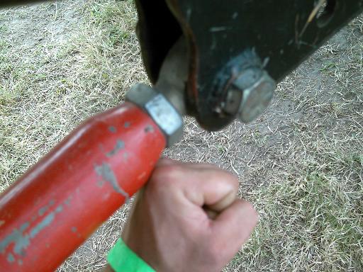 Red painted metal rod connected to a black bracket with a large bolt