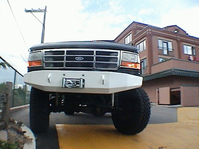 Front view of lifted white Ford SUV with winch bumper and big tires