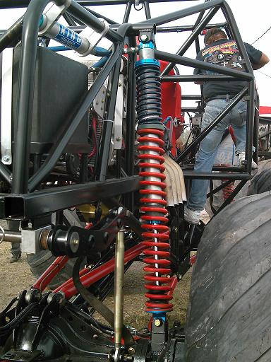 1986 Ford Bronco - Close-up of a monster truck's heavy-duty suspension system, with a mechanic attending to it.