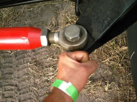 1986 Ford Bronco - Close-up of a red suspension component being held by a hand with a green wristband.