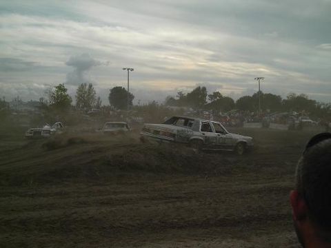 1986 Ford Bronco - Several cars compete in a demolition derby event, with one vehicle prominently displaying "WILD THING" on its door.