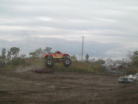 1986 Ford Bronco - Monster truck 'Gun Slinger' jumps over a car during an event.