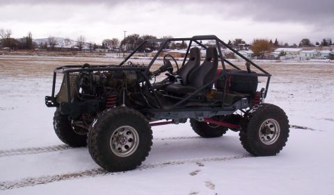 1984 Ford Bronco - This custom-built buggy features a roll cage, racing seats, and large off-road tires, seen here in a snowy landscape.