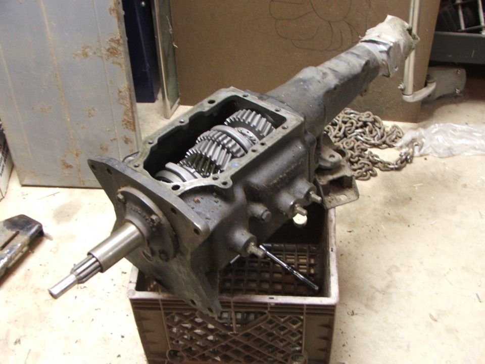 Transmission with gears exposed, resting in a plastic crate