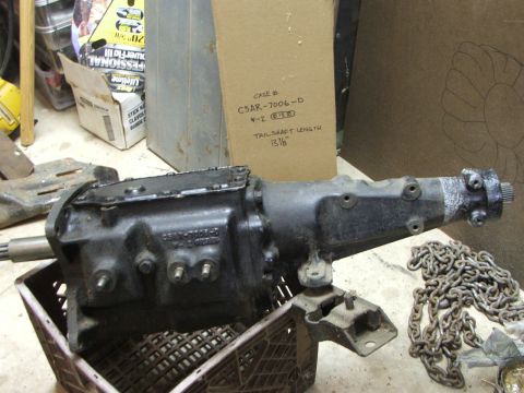 1965 Ford Mustang - A transmission part is shown in a crate, with a cardboard box containing part information in the background.