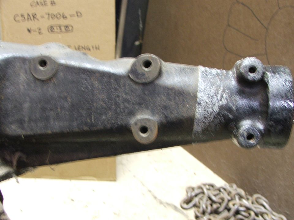 Black automotive part with four bolt holes and a silver metal end with two bolt holes