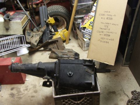 1965 Ford Mustang - A transmission is shown in a crate next to a cardboard box with handwritten part numbers and specifications.