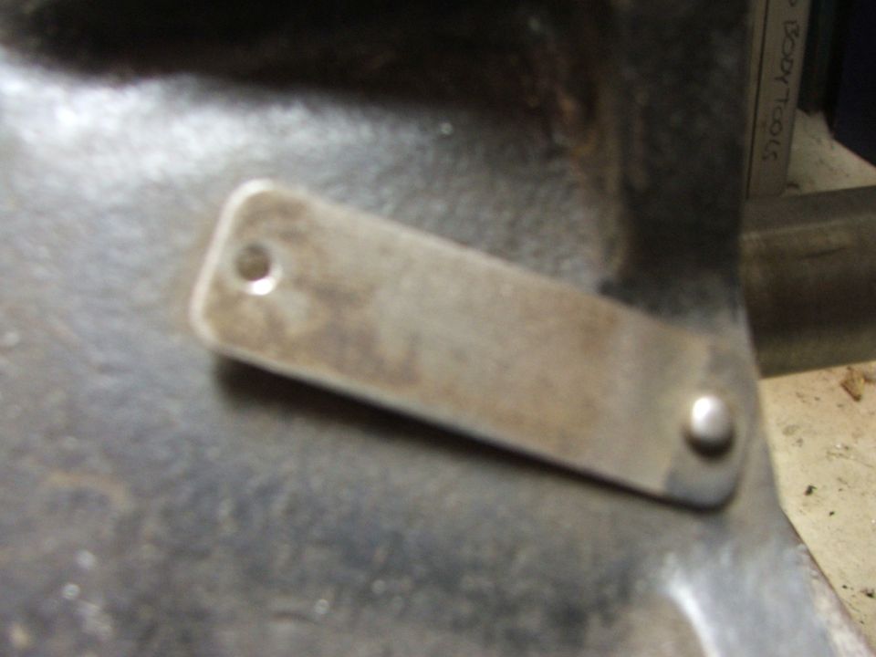 Close-up of a metal identification plate riveted to a dark, textured surface, possibly an engine block