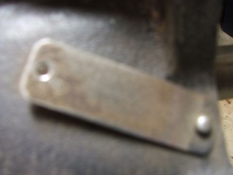 1965 Ford Mustang - A metal plate is shown attached to a surface with two rivets.