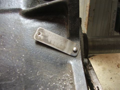 1965 Ford Mustang - Close-up of a metal plate attached to an engine component, with visible rivets and texture.
