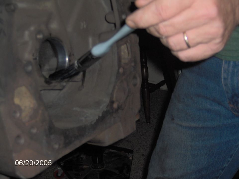 Close-up of a person's hand using a brush on an engine block