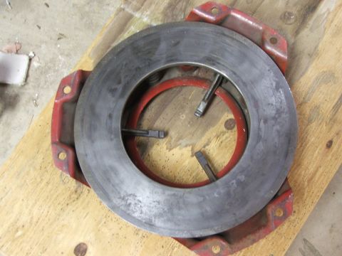 1965 Ford Mustang - A clutch pressure plate with a red diaphragm spring is shown, resting on a wooden surface.
