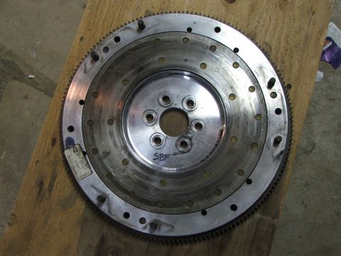 1965 Ford Mustang - Flywheel part with SBF marking, resting on a wooden surface.