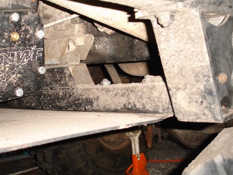 1989 Ford Bronco - Close-up view of the undercarriage of a vehicle, showing suspension parts and a tire supported by a jack.