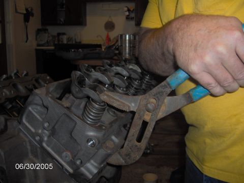1978 Ford Bronco - A person works on an engine's valve train, using pliers to manipulate a valve spring.