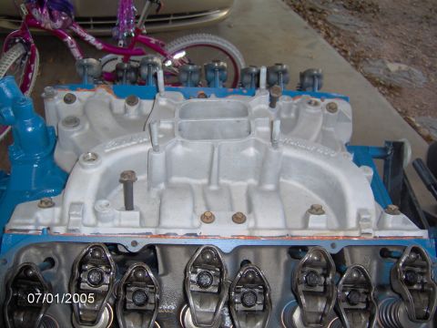 1978 Ford Bronco - Close-up view of an engine's intake manifold and valve train, with a bicycle in the background.