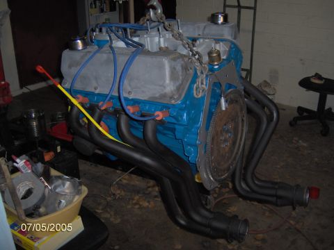1978 Ford Bronco - A V8 engine assembly, painted blue and silver, is prepared for installation with custom exhaust headers.
