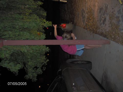 1978 Ford Bronco - A young girl holds a red lantern while standing near a tree and a car on a sidewalk.