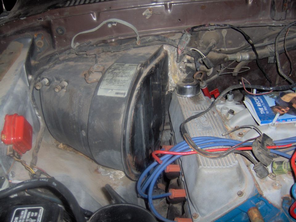 Engine bay showing a large black heater core housing and engine components with blue and red spark plug wires